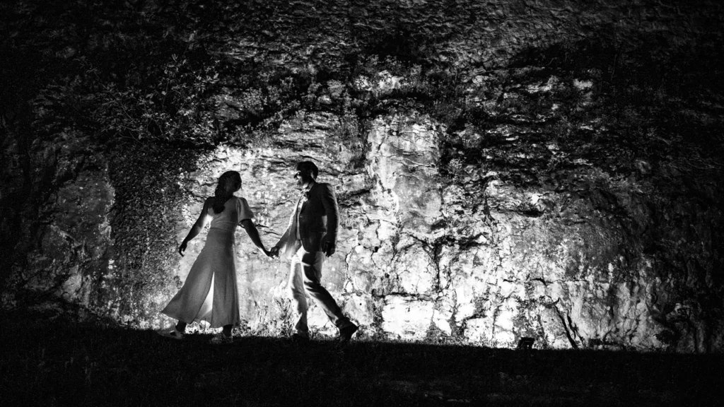 Photographe de mariage à Lyon : séance couple nocturne en contre-jour devant un mur de pierres.